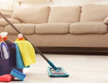 Bucket with cleaning products placed in front of living room couch