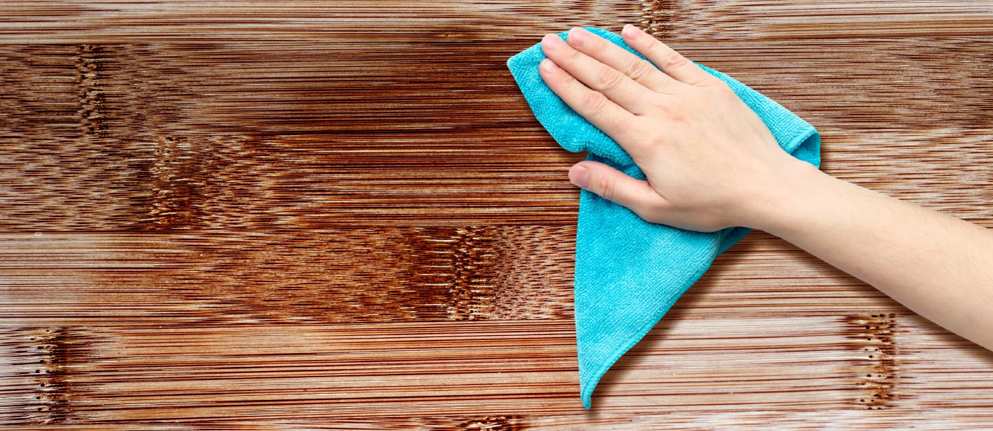 Person cleaning wood furniture with cloth