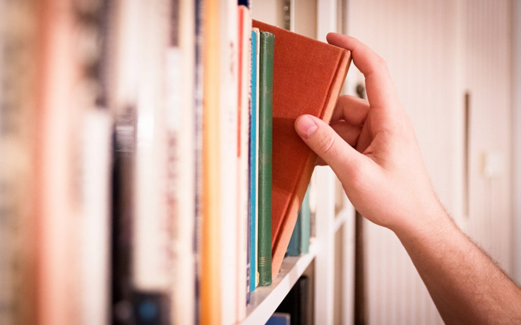 Man picking a Islamic book from shelf