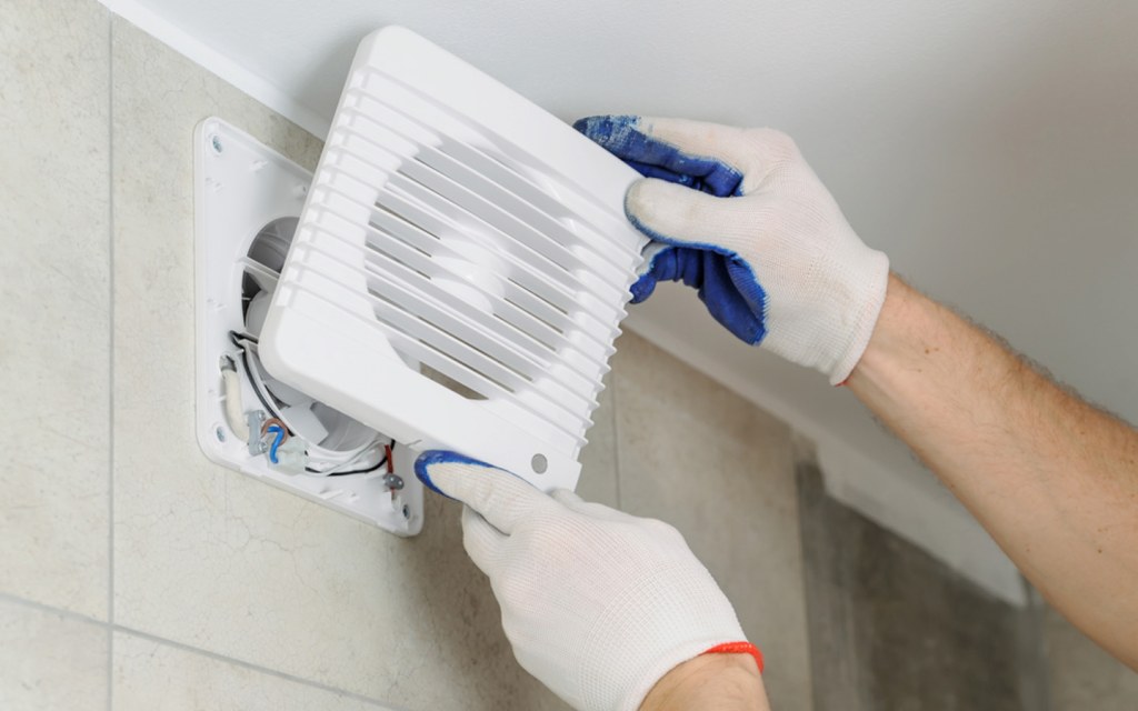 Man installing exhaust fan in kitchen